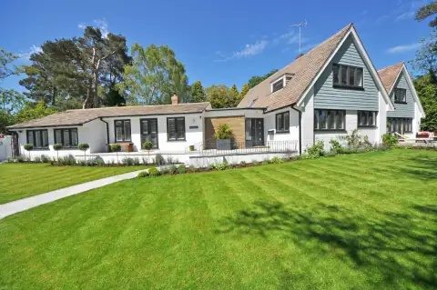 A freshly mowed lawn in front of a white two-storey home